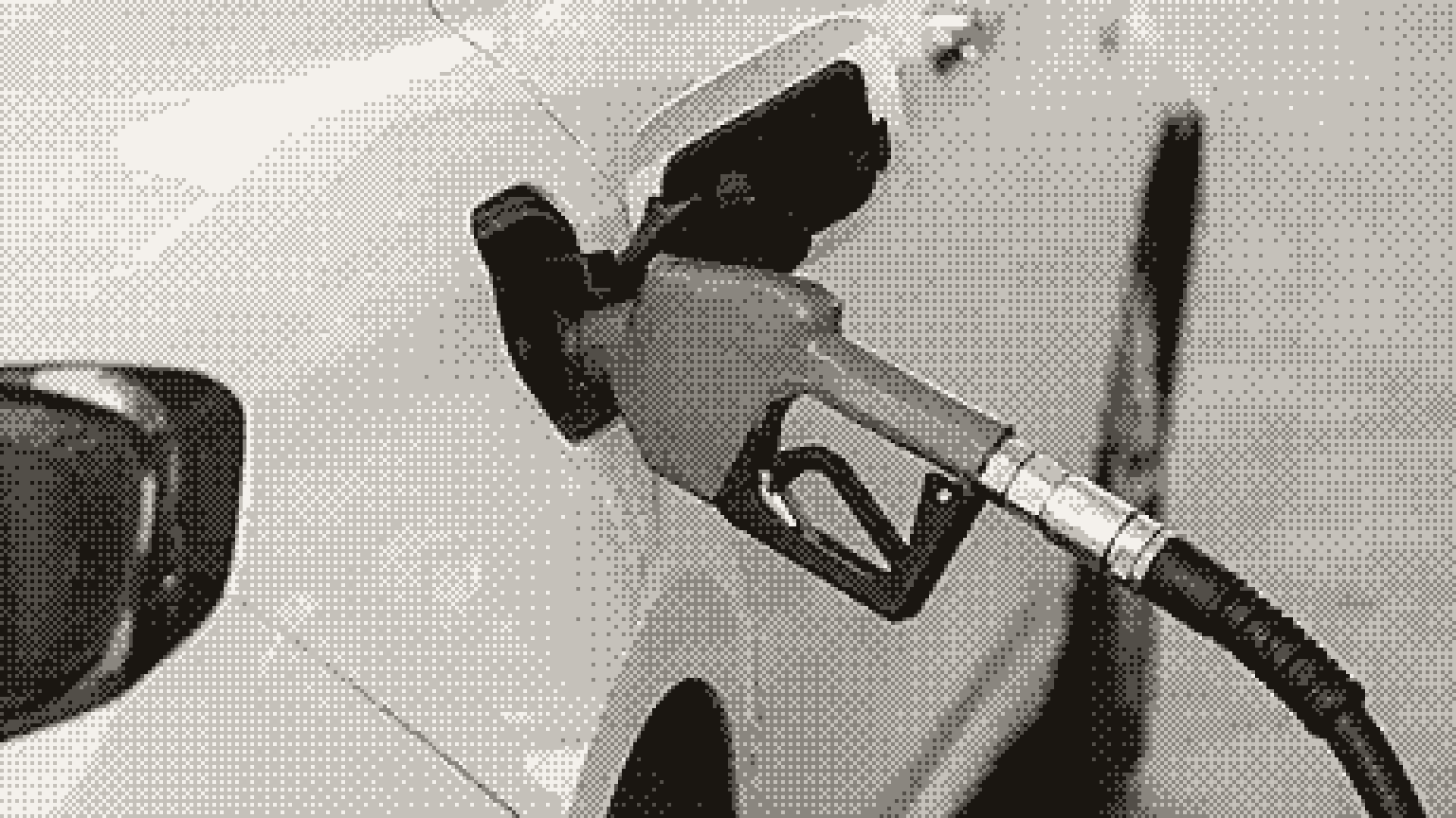 A fuel nozzle resting in the filler of a white car