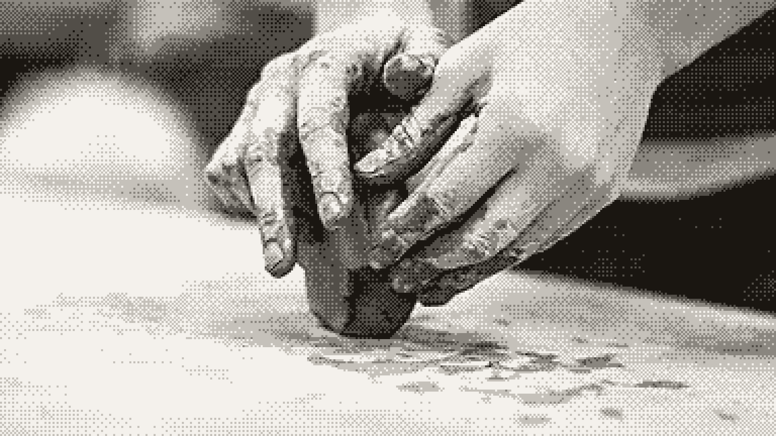 Hands shaping a lump of clay on a workbench